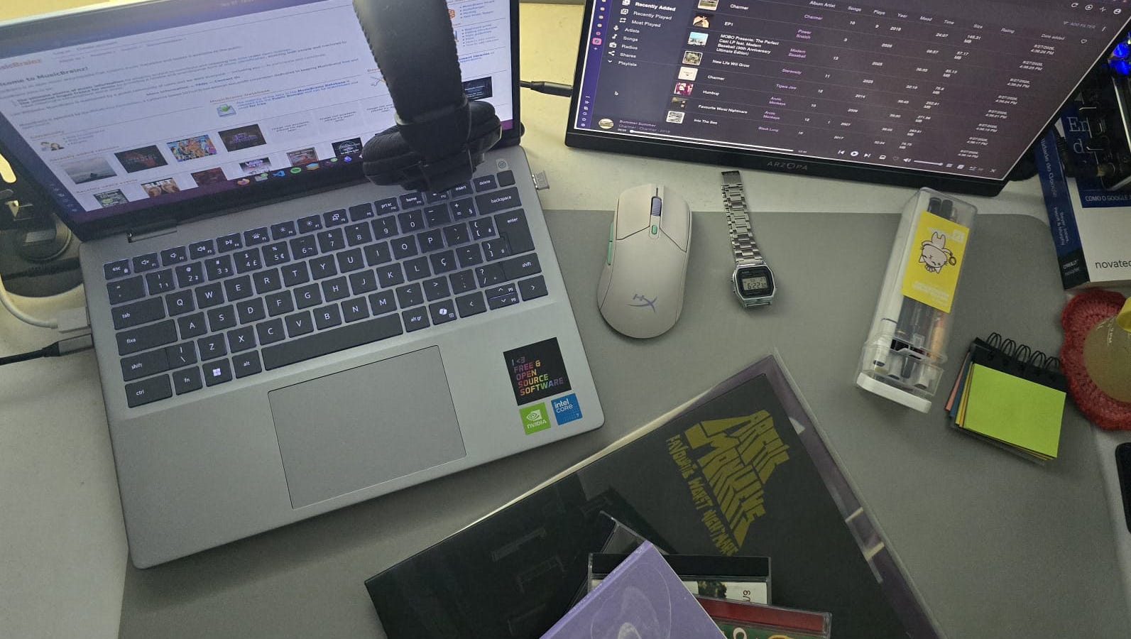 Desk with a laptop, a monitor showing the Navidrome library, headphones and Arctic Monkeys' Favourite Worst Nightmare on vinyl