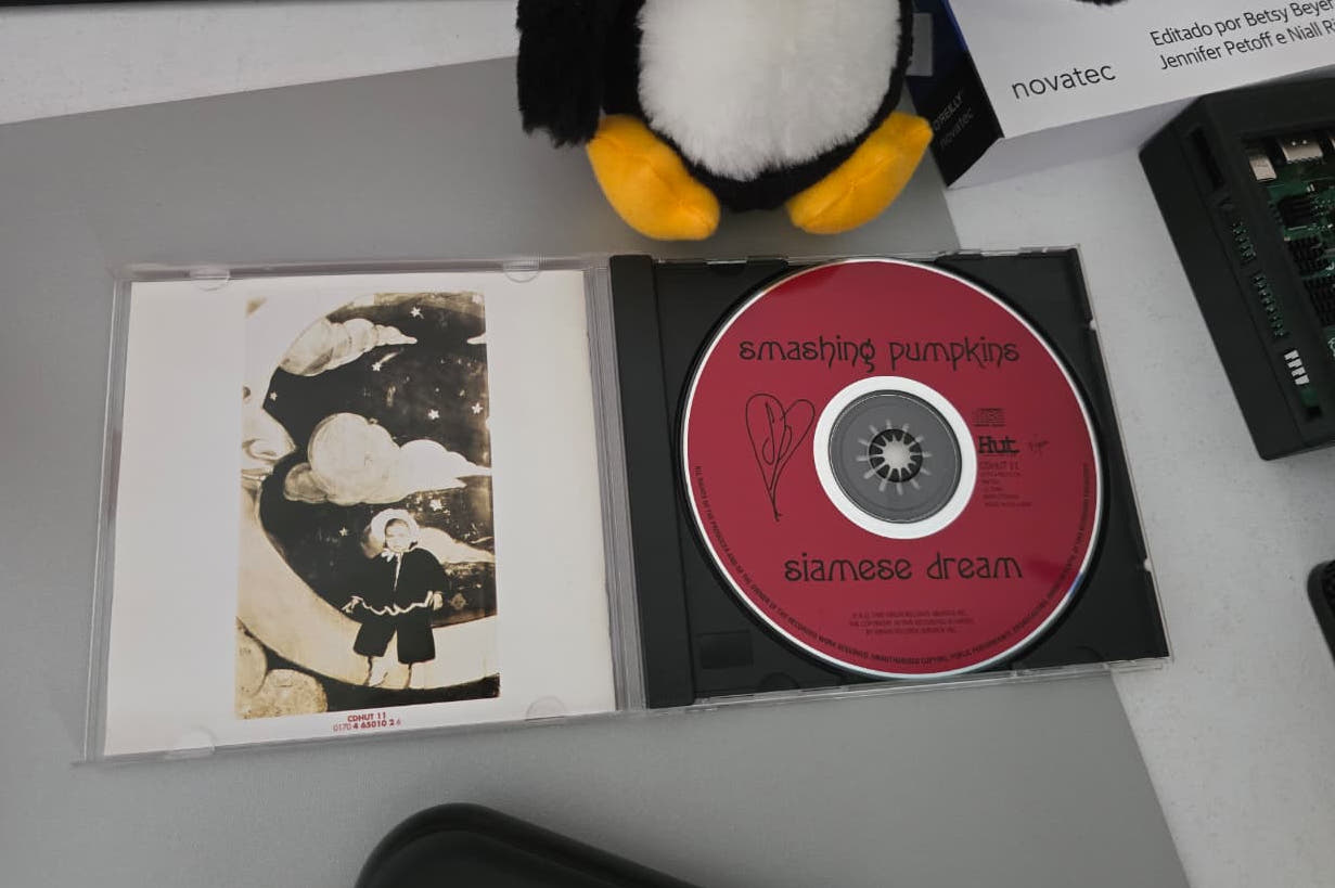 Estojo do CD Siamese Dream aberto: o disco vermelho e a arte sépia do encarte, com uma criança em pé sobre uma lua crescente